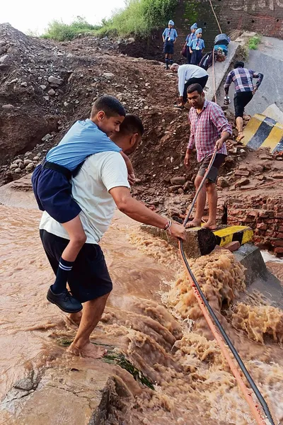 बच्चों को स्कूल भेजने के लिए कंधे पर उठा नदी पार करवाने को मजबूर अभिभावक